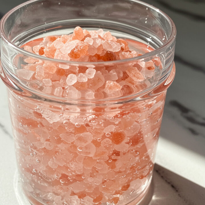 Himalayan Pink Salt Weight Loss Drink concentrate showing pink salt crystals dissolving in water inside a clear glass jar.