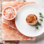 Himalayan pink salt block cooking setup with seared golden brown scallops