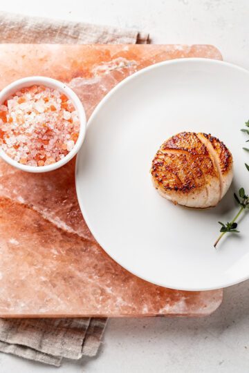 Himalayan pink salt block cooking setup with seared golden brown scallops