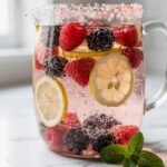 Berry citrus pink salt infused water recipe in a clear glass pitcher
