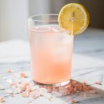 A simple glass of lemon water with pink Himalayan salt for hydration.