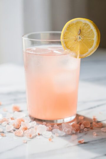A simple glass of lemon water with pink Himalayan salt for hydration.