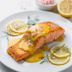 Pan-seared salmon with pink salt citrus butter on a white plate.