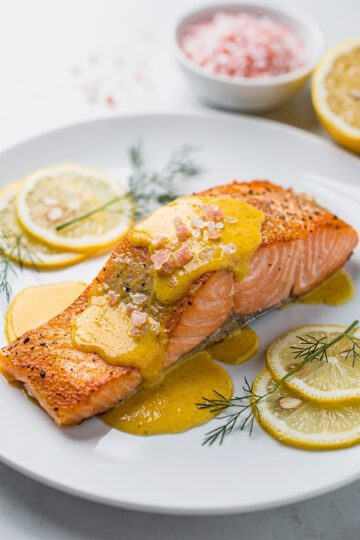 Pan-seared salmon with pink salt citrus butter on a white plate.