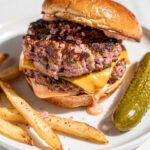 Pink salt smash burger with crispy crust and melted cheese on potato bun.