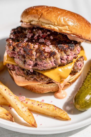 Pink salt smash burger with crispy crust and melted cheese on potato bun.