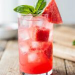 Refreshing watermelon basil cooler with pink salt garnish in clear glass.