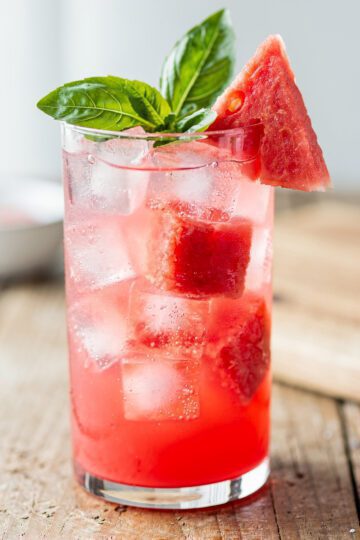 Refreshing watermelon basil cooler with pink salt garnish in clear glass.