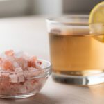 Himalayan pink salt trick recipe glass with lemon wedge on marble counter