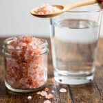 Pink Himalayan salt for fasting in a glass jar with lemon water