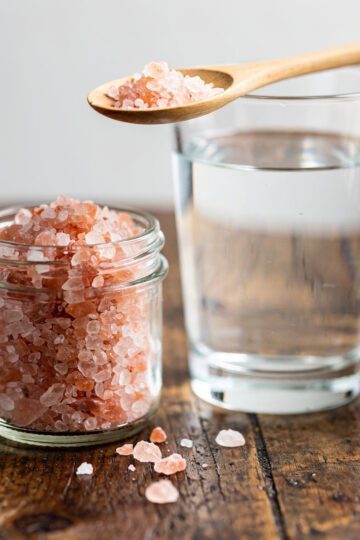 Pink Himalayan salt for fasting in a glass jar with lemon water