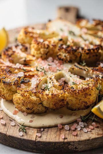 Pink salt roasted cauliflower steaks with crispy edges and lemon tahini sauce