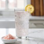 Chia seed water with pink salt and lemon slice on marble.