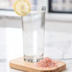 Clear glass cortisol water with pink salt on marble countertop