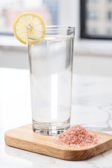 Clear glass cortisol water with pink salt on marble countertop