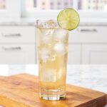 Pale golden tan lime water in glass on marble countertop