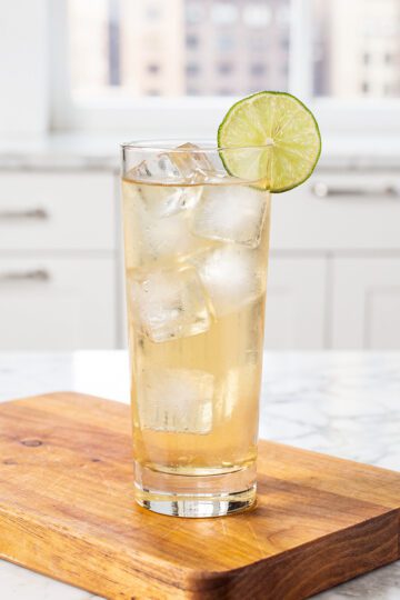 Pale golden tan lime water in glass on marble countertop