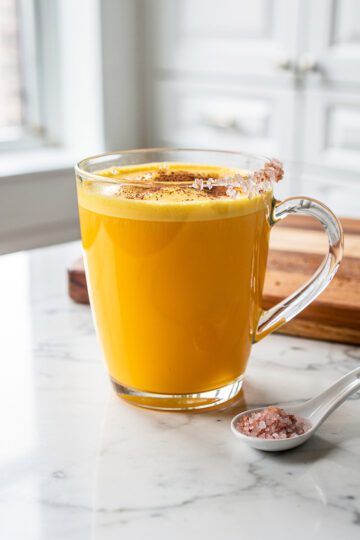 Golden milk latte in clear mug on white marble countertop