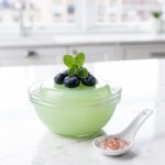 Vibrant matcha gelatin dessert in clear glass bowl, glossy jade green.