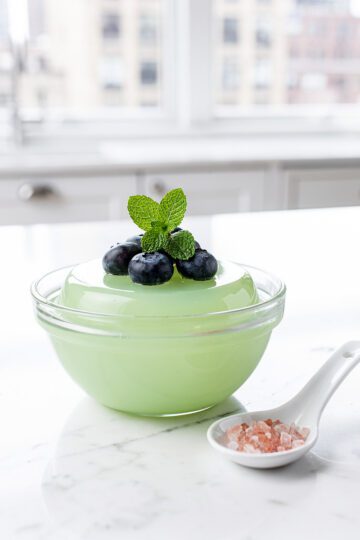 Vibrant matcha gelatin dessert in clear glass bowl, glossy jade green.