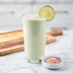 Creamy pale green keto smoothie on white marble countertop
