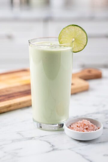 Creamy pale green keto smoothie on white marble countertop